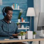 young-manager-using-headphones-listen-music-while-working-from-home-office-computer-pc-1