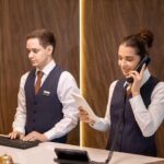 one-of-two-young-hotel-receptionists-looking-at-to-2021-09-24-03-41-39-utc-scaled-e1681390736601